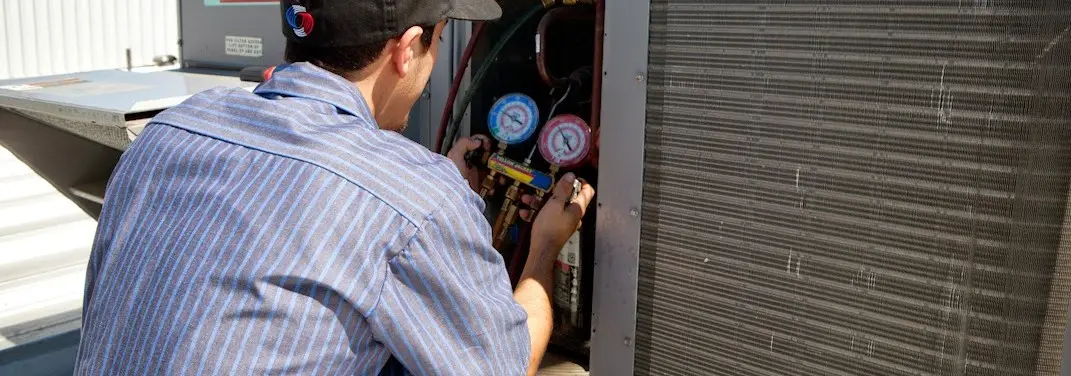 HVAC technician servicing a condenser unit in Stratford